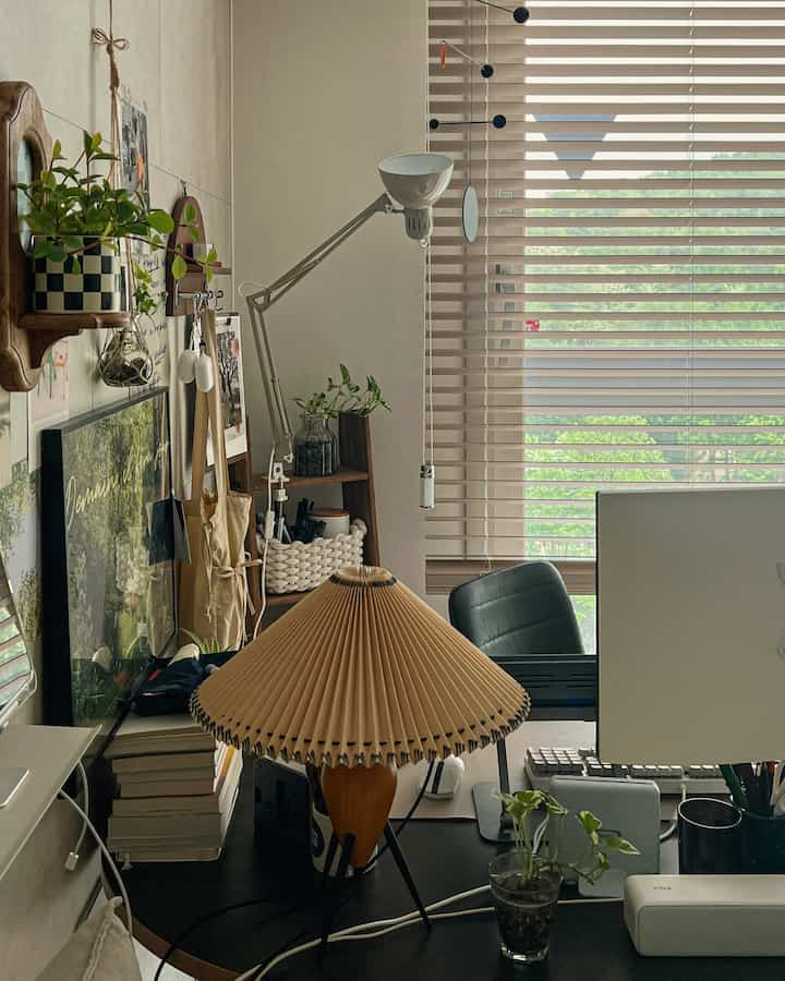 Natural beige blinds with black desk, lighting, and plants in a cozy home office space