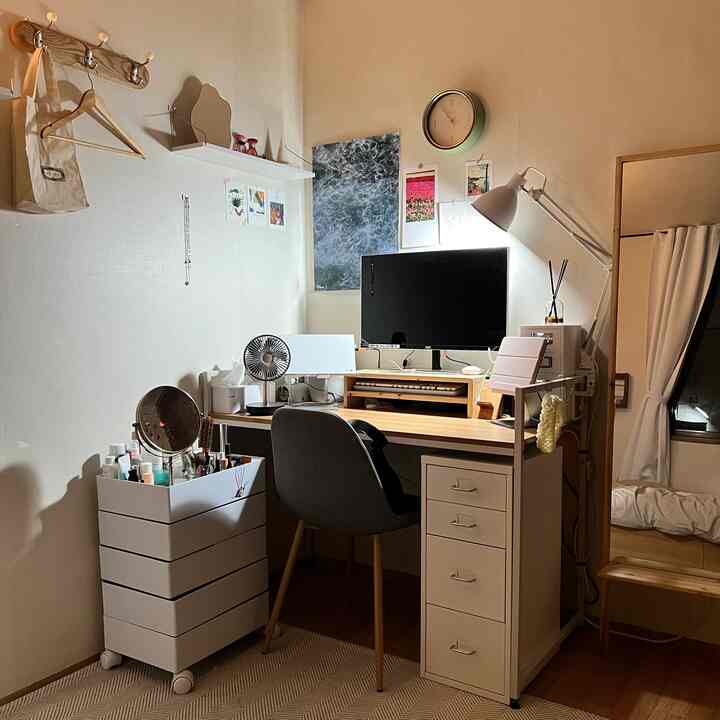 Beige-toned small home office featuring natural wood desk, office chair, neat storage cabinet, and desk lamp in a minimalistic setup