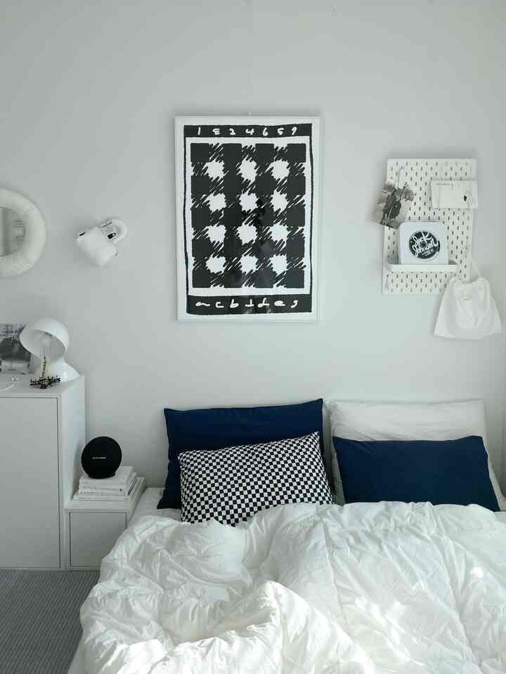 白とネイビーカラーの寝室、白い掛け布団とネイビーの枕が配置されたシンプルモダンなインテリア