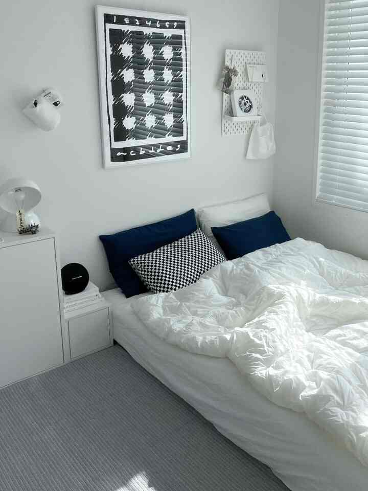 White and navy toned bedroom featuring tidy bedding and modern wall art in a clean, minimalist space