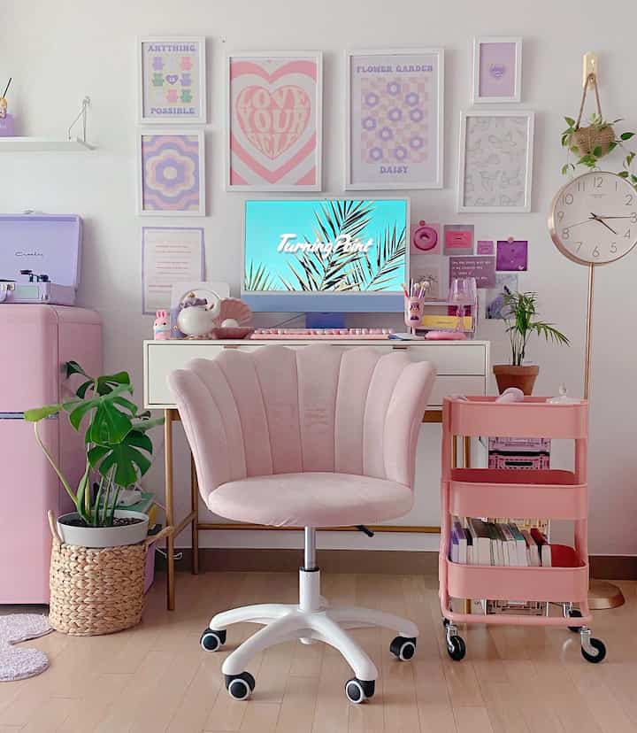 ピンクとホワイトのトーンのホームオフィス、ピンクのデスクチェアとトロリーが配置されたかわいらしく整ったインテリア