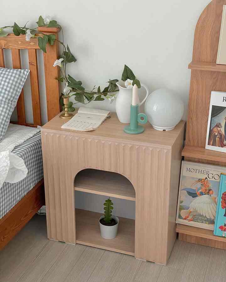 Bedroom featuring wood tone furniture and white walls, with a nightstand decorated by objets and plants creating a cozy atmosphere