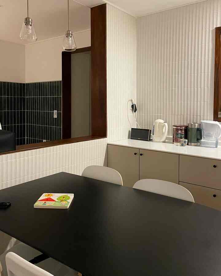 A modern kitchen space with earth tones featuring a black dining table and white dining chairs, creating a cozy atmosphere