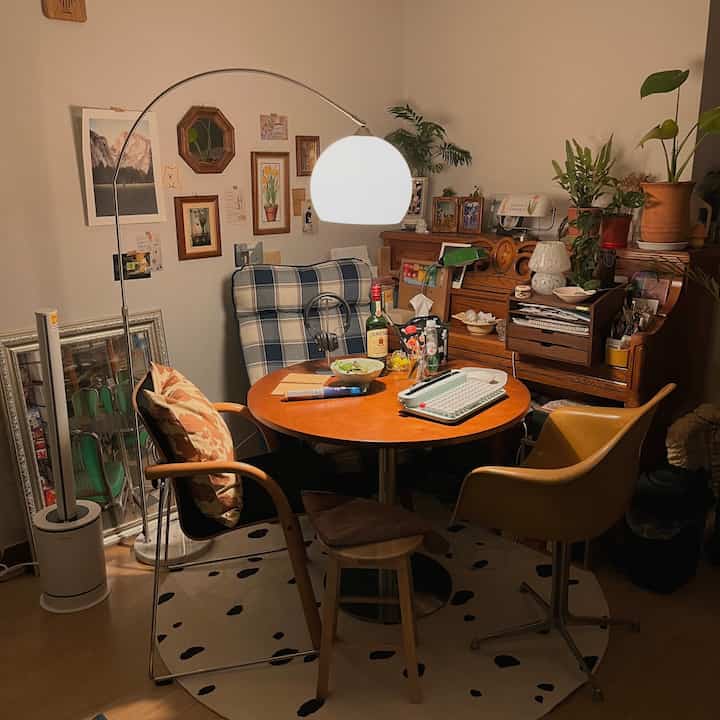 Warm wood tones define this natural dining room featuring a round table, framed wall art, and abundant greenery creating a cozy atmosphere