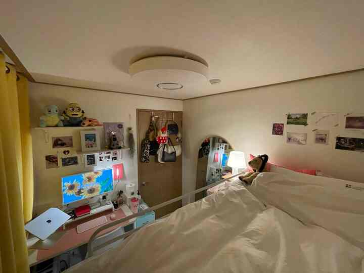 White and yellow toned small bedroom featuring a bunk bed, desk, full-length mirror, and warm lighting