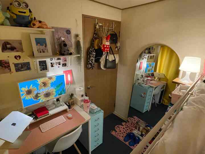 ベージュとパステルトーンのコンパクトな寝室、二段ベッドの下にデスクとドレッサーが配置された居心地の良いホームオフィス空間