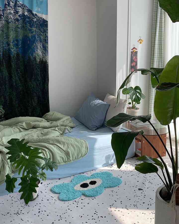 青と緑のトーンが調和したワンルーム寝室、豊かな緑の植物と柔らかな自然光が印象的な空間