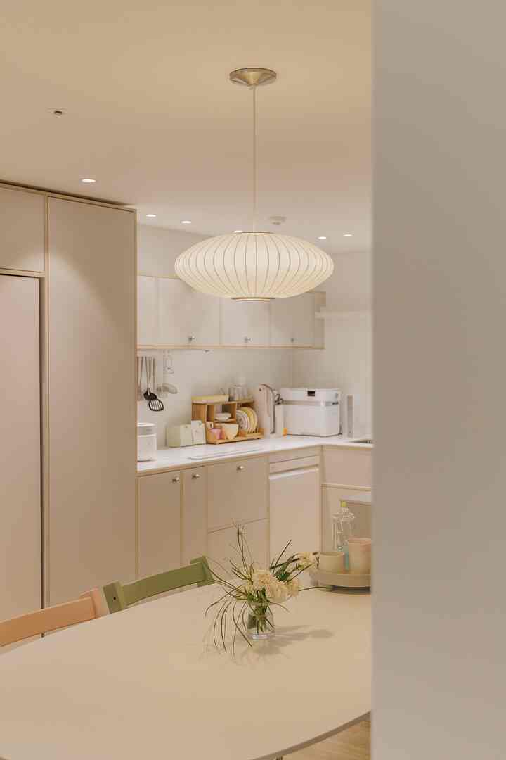 Natural and white toned kitchen featuring a central pendant light and Tripp Trapp dining chairs with a warm, cozy atmosphere
