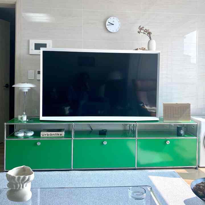 Minimalistic living room with white walls and modern green TV stand