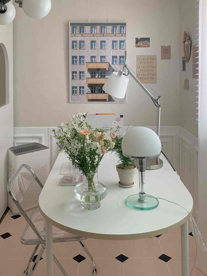 Beige-walled home office with white furniture, featuring a vase of flowers and table lamps creating a cozy atmosphere