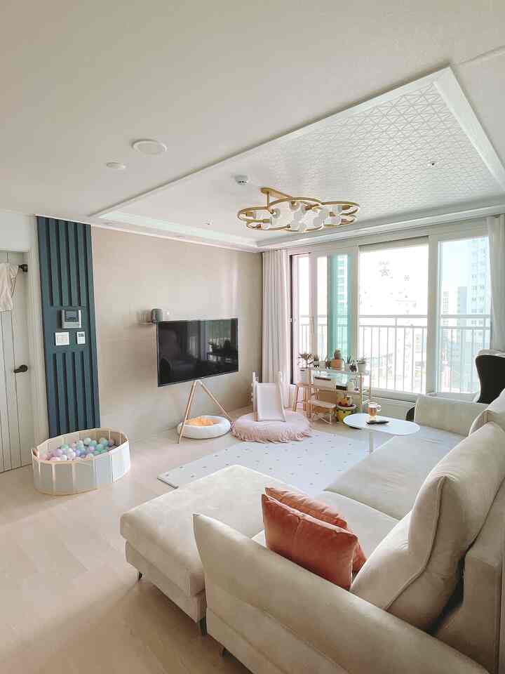 Bright natural beige toned living room featuring large sectional sofa and children's play equipment in a family-friendly space