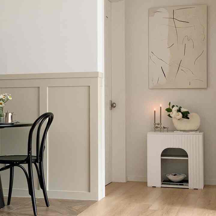 ホワイトとナチュラルカラーのダイニング、コーナー収納とウォールアート、キャンドルが温かみを演出する雰囲気あるインテリア