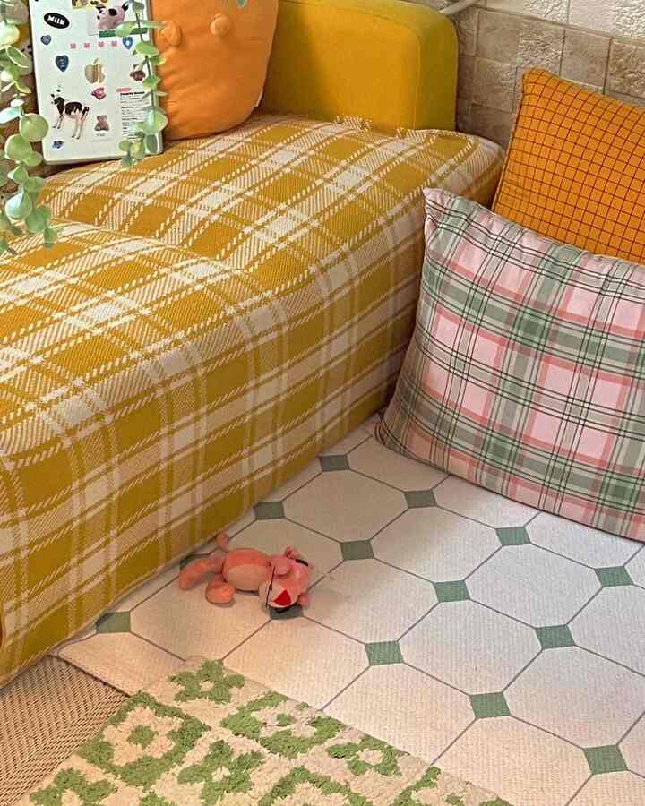 Yellow-toned living room featuring a checkered sofa, various cushions, and rugs creating a cozy atmosphere