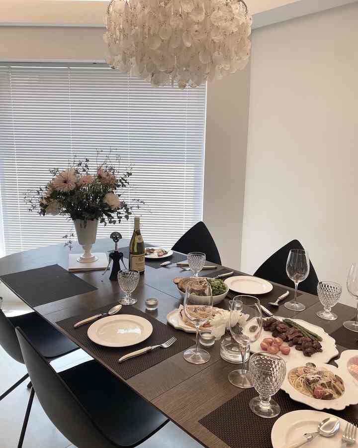Modern dining room in white and black tones featuring a table set with plates, wine glasses, and a vase creating a refined atmosphere