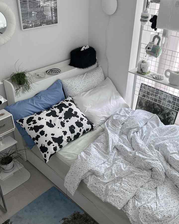 White and blue toned bedroom featuring patterned duvet cover and assorted pillows in a modern setting