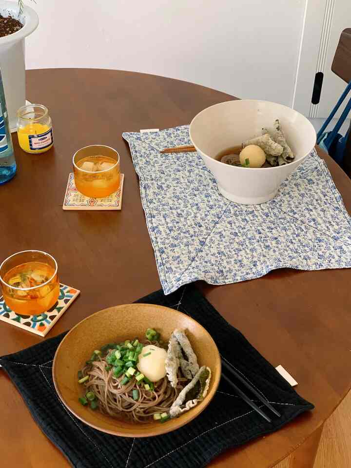 Natural dining space with wood tone wooden table featuring two bowls of buckwheat noodles and drinks
