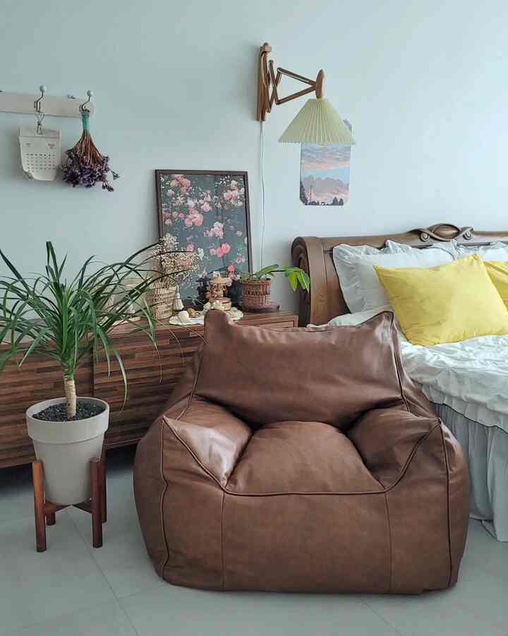 Bright white bedroom featuring wood tone furniture, brown bean bag, and yellow cushions creating a natural modern vibe
