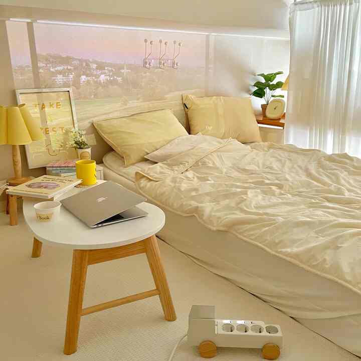 Soft beige-toned bedroom featuring comfortable bedding, wooden table, and bright natural light creating a cozy atmosphere