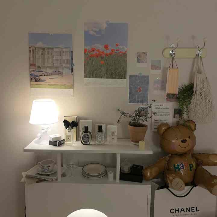 A cozy living room with white walls and console featuring lighting, potted plant, candle, and a bear-shaped balloon