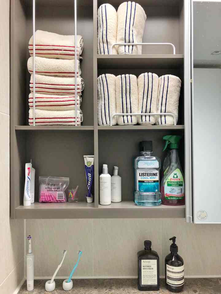 Clean bathroom space featuring white and brown toned shelves neatly organized with towels and bath products
