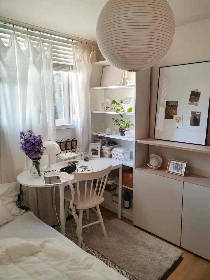 Bright white and beige bedroom with a home office setup featuring a desk, chair, bookshelf, and soft natural tones creating a cozy atmosphere.