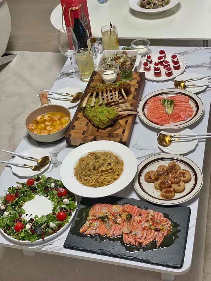 ホワイトトーンのキッチンスペース、テーブル上に洋食料理とゴールドのカトラリーが並ぶクリスマスの雰囲気の食事風景