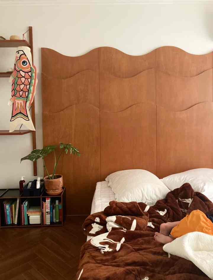 Natural wood-tone bedroom featuring a wavy wooden headboard and cozy bedding with a warm atmosphere