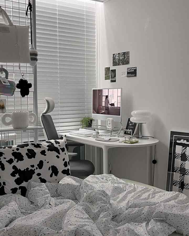 白を基調とした一人暮らしのホームオフィス空間、ブラインドとモダンなデスク、ベッドが配置された清潔感のあるインテリア