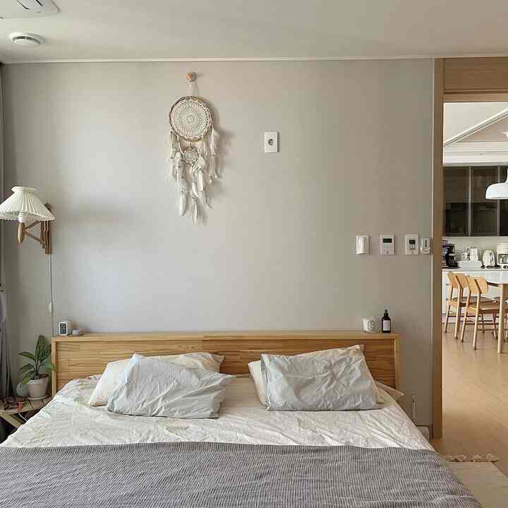Beige and white tone bedroom featuring wooden bed and wall dreamcatcher with a natural atmosphere