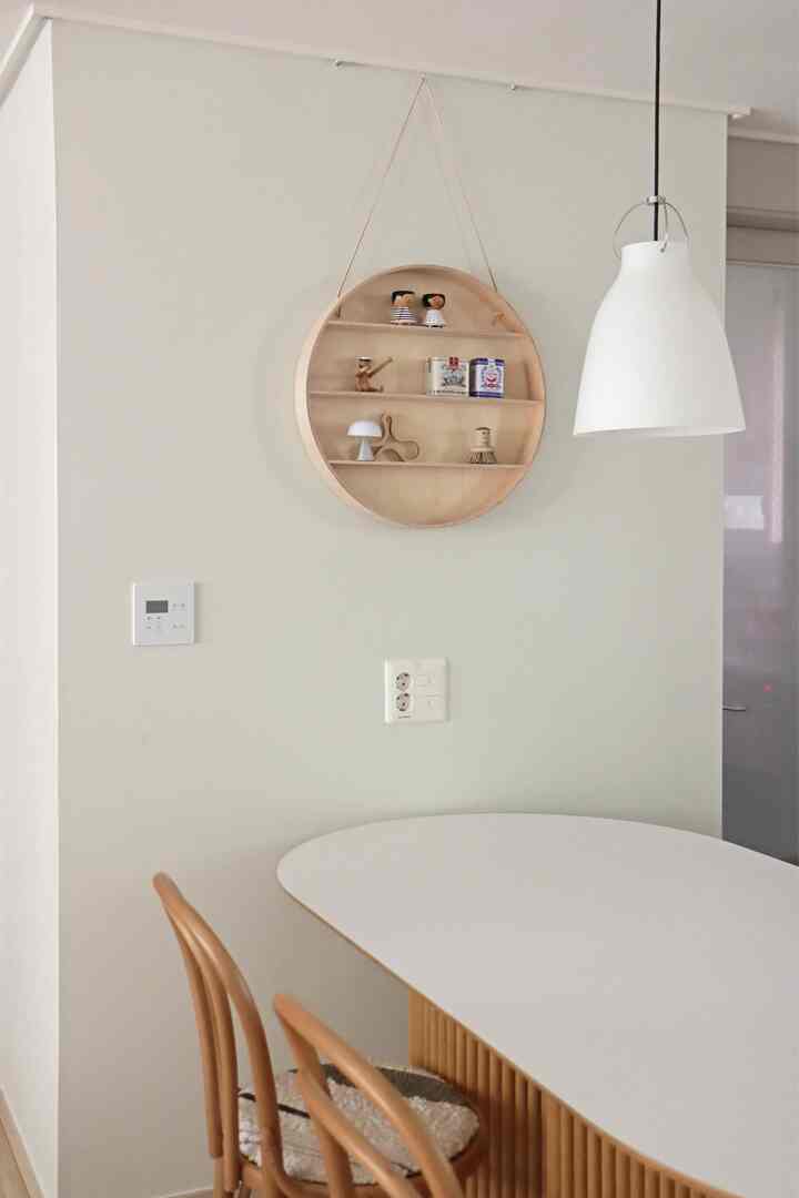 Natural-toned dining room featuring a round wall shelf and a white pendant light, creating a clean and bright atmosphere