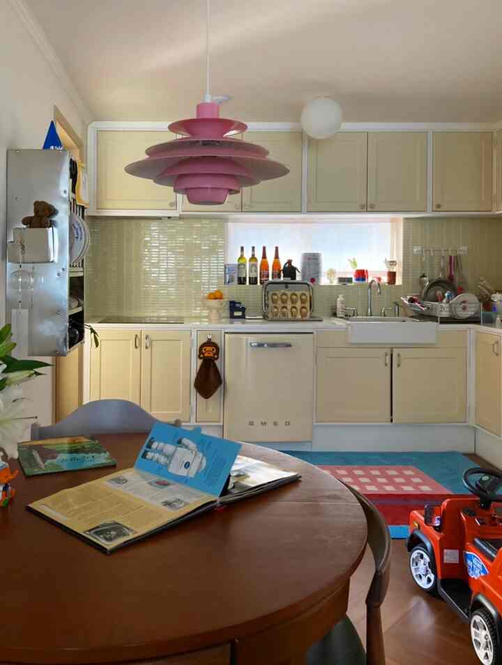 Light brown and natural tone kitchen featuring round dining table, pink pendant light, and cozy home cafe atmosphere