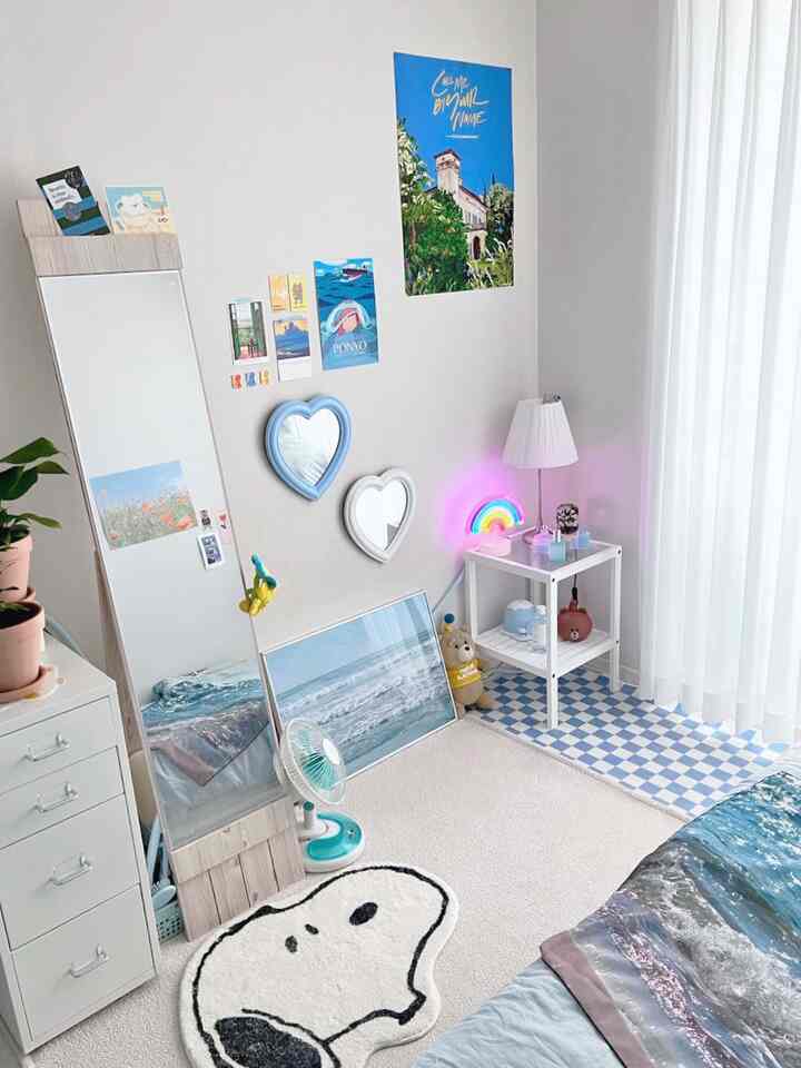 ホワイトベースとブルートーンが調和したかわいらしい寝室、全身鏡とハート型ミラー、サイドテーブルが配置された清潔感ある空間