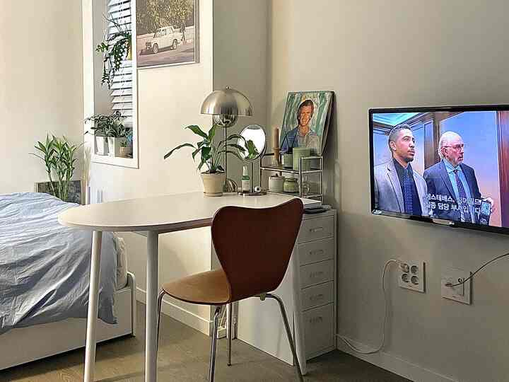 White and natural brown toned bedroom and dining area featuring plants and simple furniture in a cozy single household space