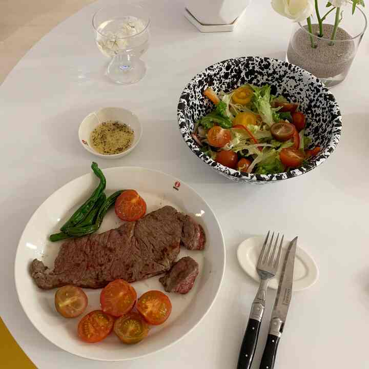Simple home cooking table setting with steak and salad on a white round dining table