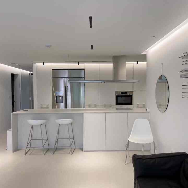 White-toned face-to-face kitchen featuring a central island with bar stools, clean and modern atmosphere