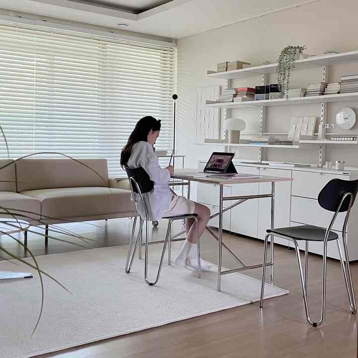 White and beige toned living room featuring a simple modern desk and sofa in a quiet study space