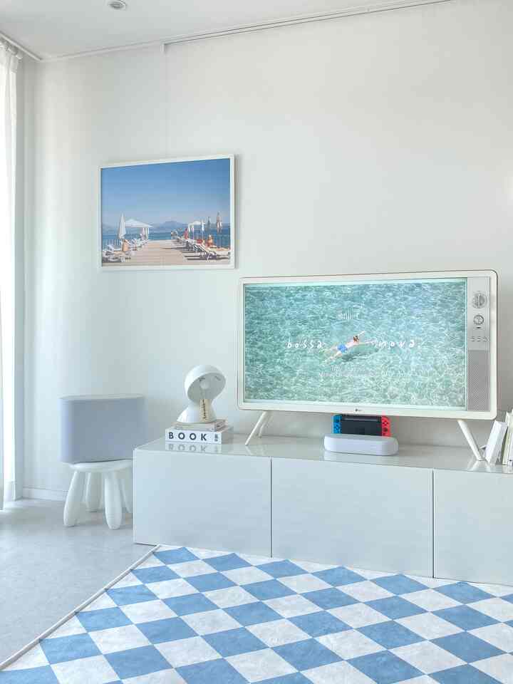 White and blue toned living room featuring a retro TV, TV stand, and checkered floor rug with a minimalist vibe