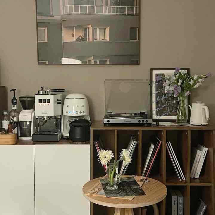Beige wall and wood-tone furniture in a cozy home cafe featuring coffee machines and decor items