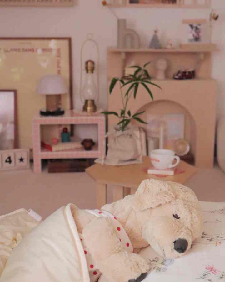 ベージュと木目調のリビング、ぬいぐるみの犬とコーヒーカップが置かれたサイドテーブルと植物が配置された雰囲気のある空間