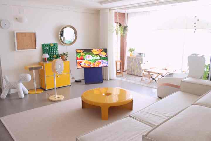 Modern living room in yellow and white tones featuring a round coffee table and large sofa with bright, airy atmosphere