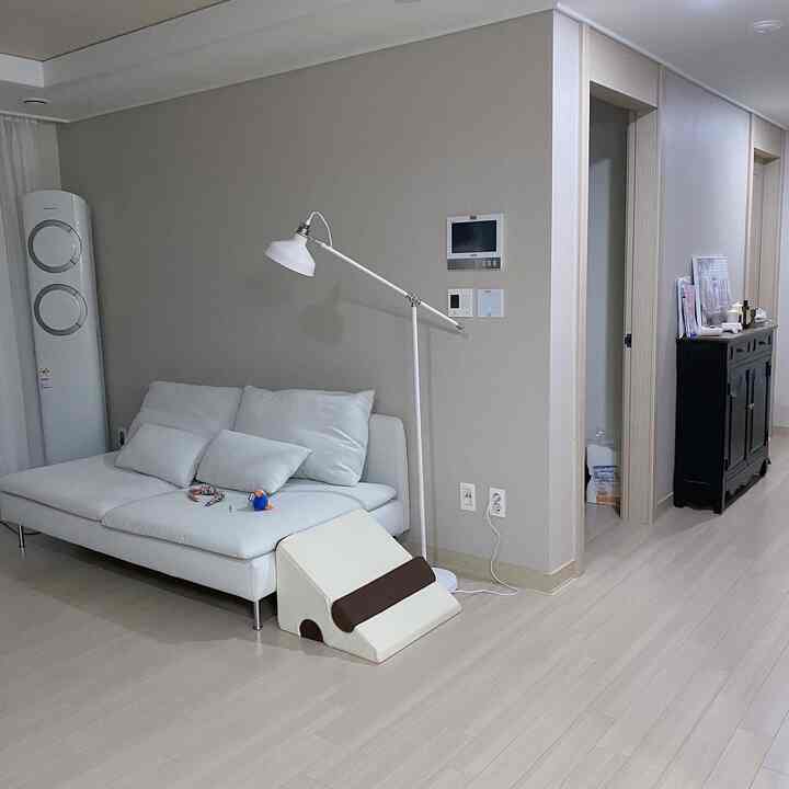 明るいベージュの壁と白いソファ、フロアランプが配置されたすっきりとしたリビングのインテリア