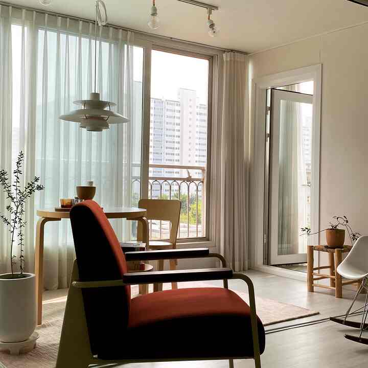 Natural toned living room featuring wooden dining table and red armchair in a bright, spacious setting