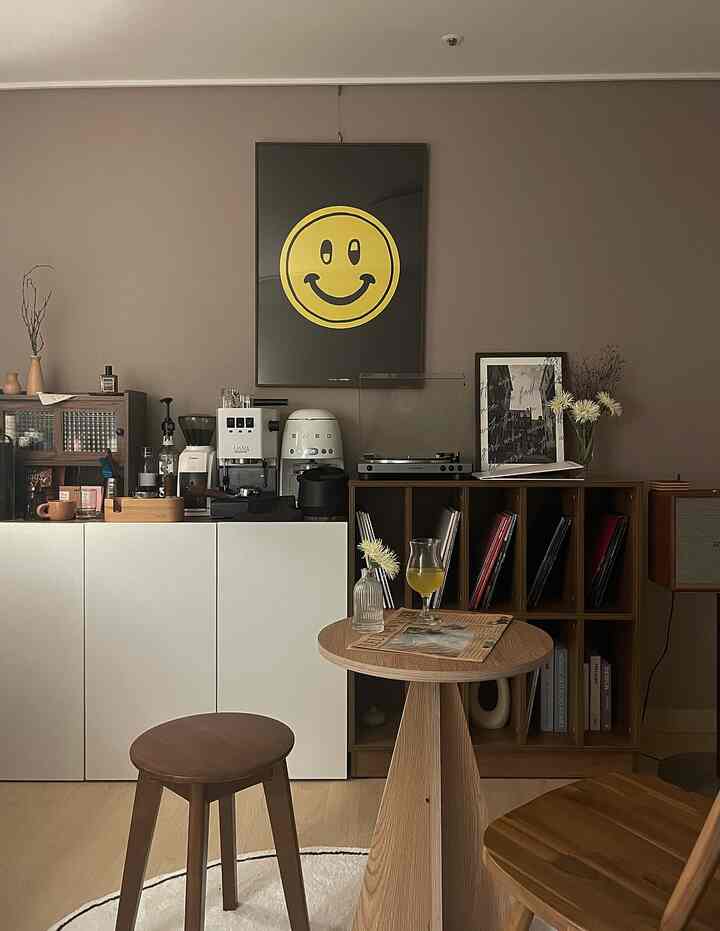 Natural wood tones and white blends in a home cafe space featuring coffee machines and a small wooden table with stools, creating a cozy atmosphere