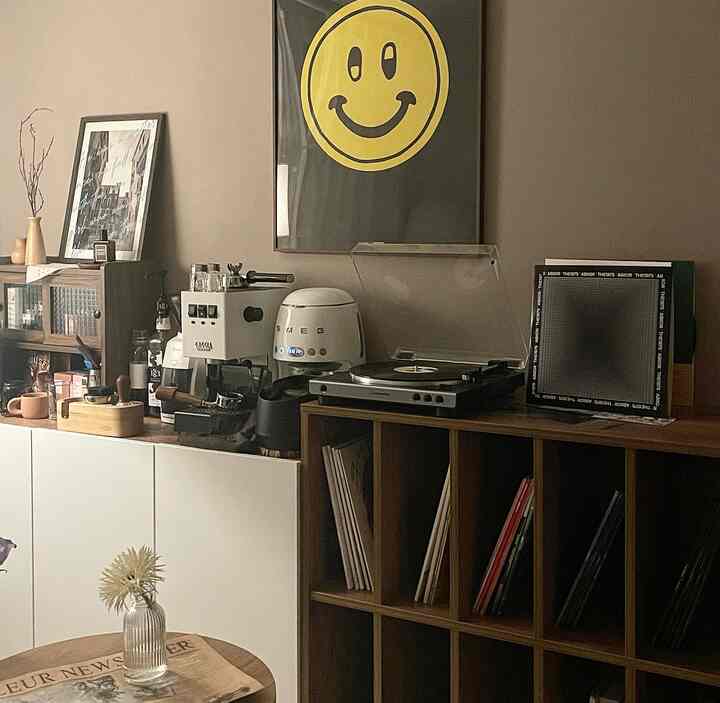 ブラウンとホワイトのトーンのカフェ風空間、LP収納やエスプレッソマシン、ポスターが配置された雰囲気のあるインテリア