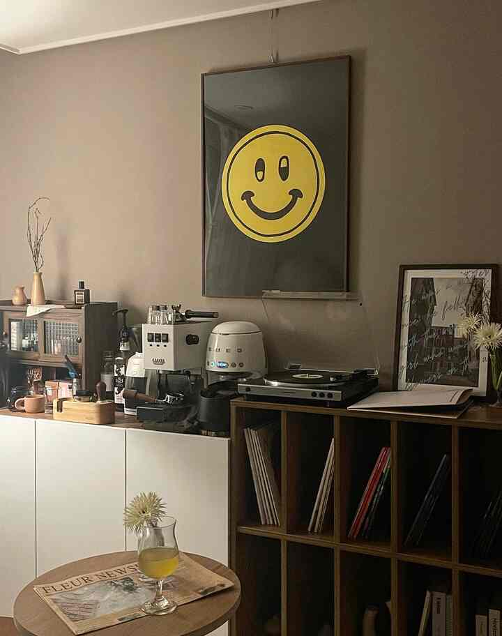 Gray-toned wall and brown wood furniture blend in a home cafe space featuring a smile poster and vintage audio devices with cozy atmosphere