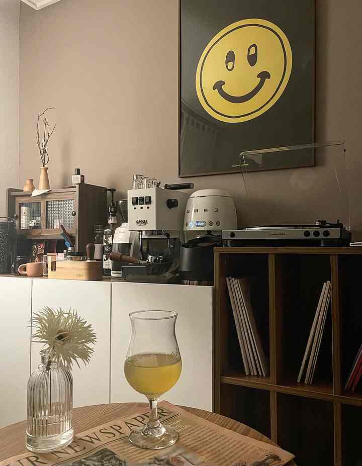 Warm brown tone wall and white cabinets in a home cafe space featuring coffee machines and a smiley poster in a cozy living room
