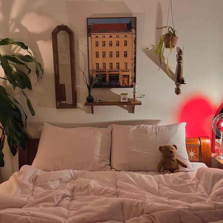 A white and wood tone bedroom featuring a teddy bear and hanging plant with cozy atmosphere