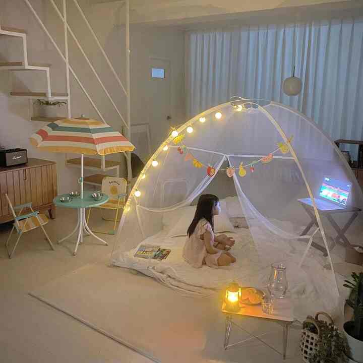 ベージュと白を基調とした子供部屋、蚊帳テントとかわいい小物が配置された温かみのある室内キャンプのインテリア