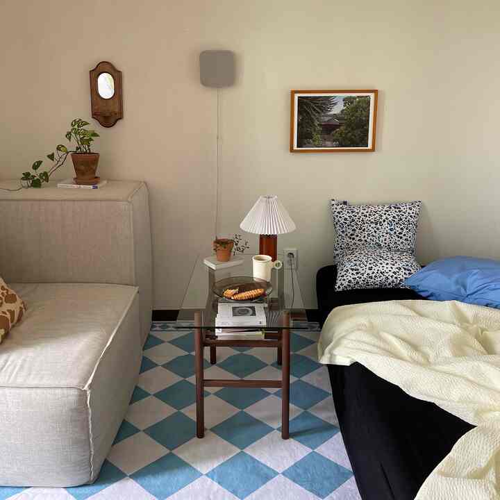 Natural beige and blue toned bedroom with glass coffee table and sofas, patterned cushions and blanket creating a cozy atmosphere