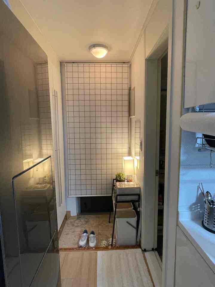 白と木目調の調和が取れたワンルームの玄関、収納棚と分別ゴミ箱が配置された印象的で落ち着いた空間